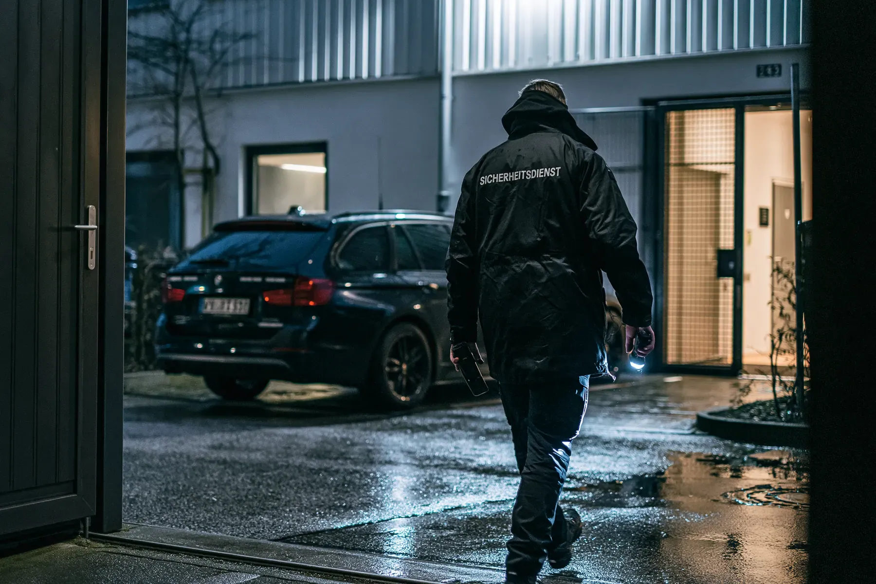 Nächtlicher Rundgang mit Taschenlampe über einen nassen Betriebshof